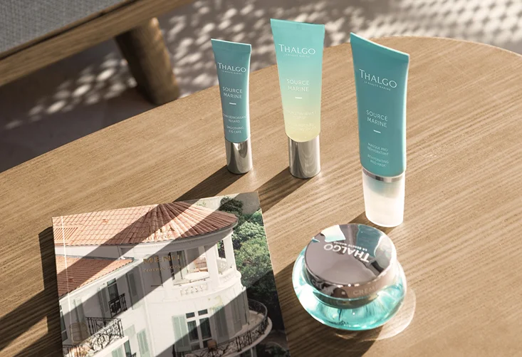 Produits de soin Thalgo Source Marine sur une table en bois avec un magazine.