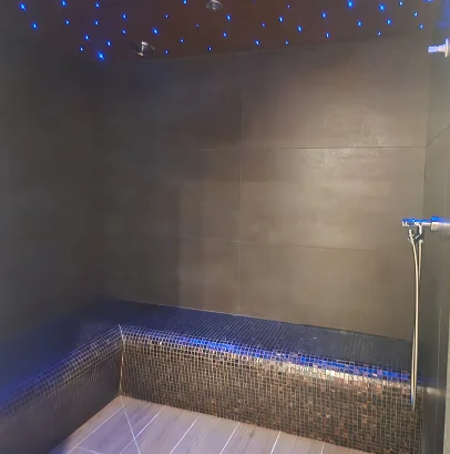 Douche de vapeur moderne avec des carreaux sombres et des lumières bleues étoilées au plafond à Bois-d’Arcy près de Versailles dans les Yvelines 78