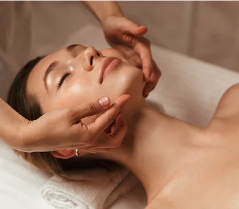 Une femme reçoit un massage facial relaxant, les yeux fermés et le visage apaisé à Bois d'Arcy près de Versailles dans les Yvelines 78